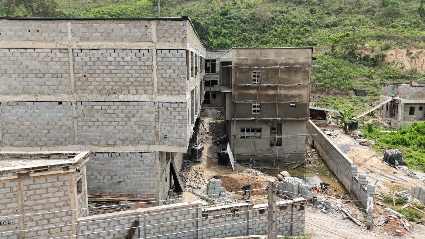 Ewang Estate under construction, 22 January 2026: blockwork complete across the blocks at three storeys, window and door openings formed, and the first render coats going on. Aerial view 1 of 7.