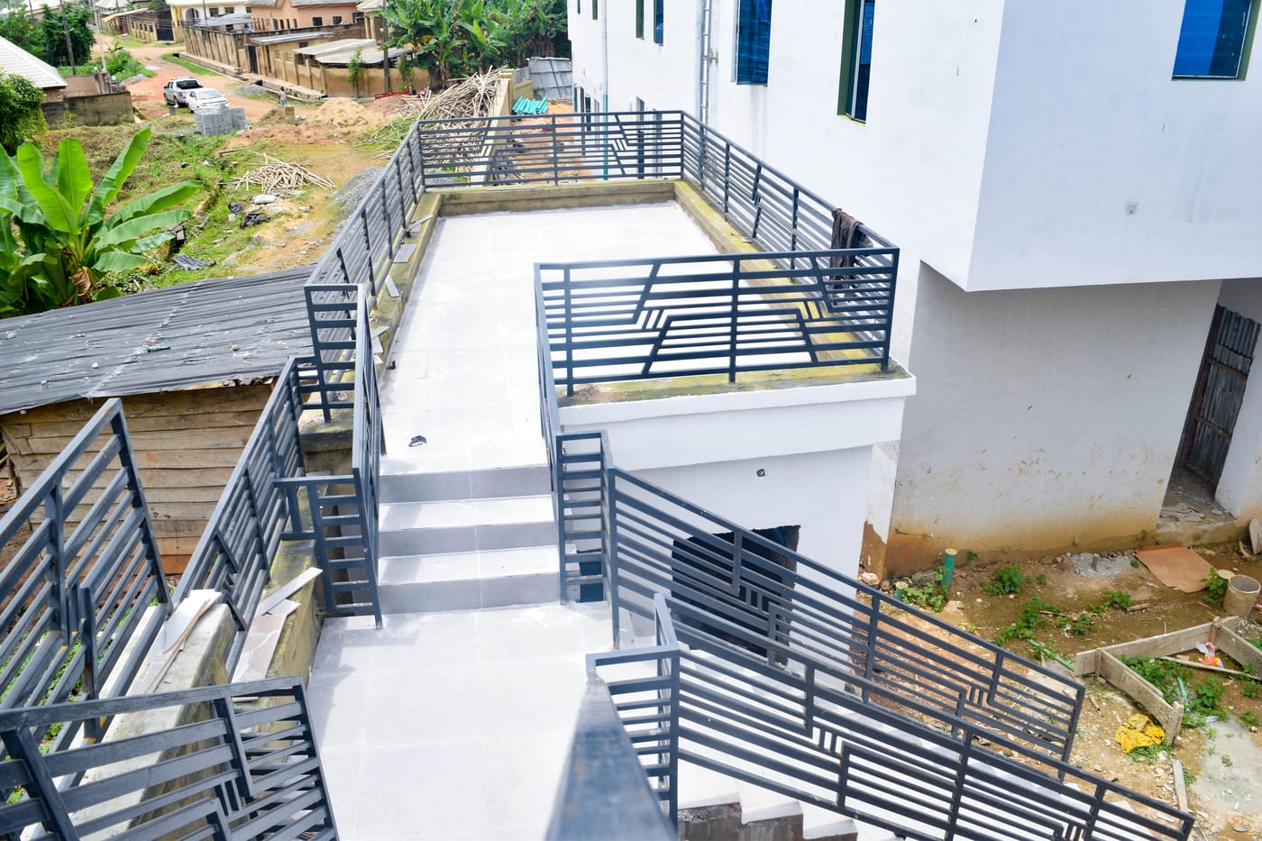 The pool terrace from above, tiled and edged with patterned metal balustrades, with steps down to the level below.